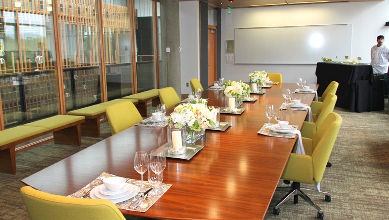 Photo of conference room in Ford Alumni Center setup with chairs, plates and floral arrangements.