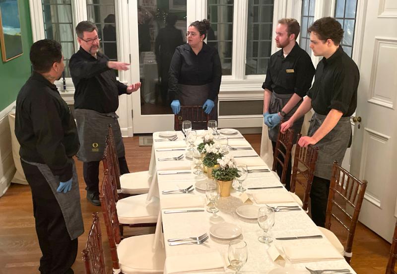 Catering staff discussing setup of banquet table.