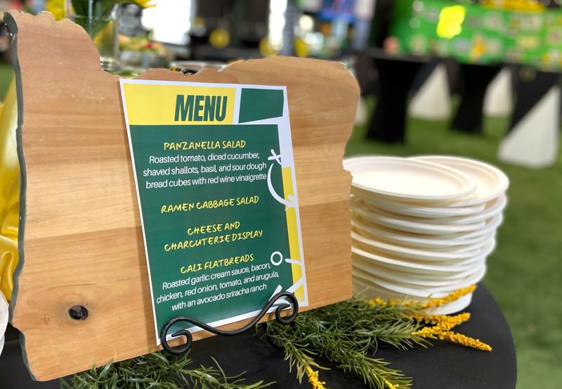 Event menu displayed on wooden cutout of the state of Oregon.